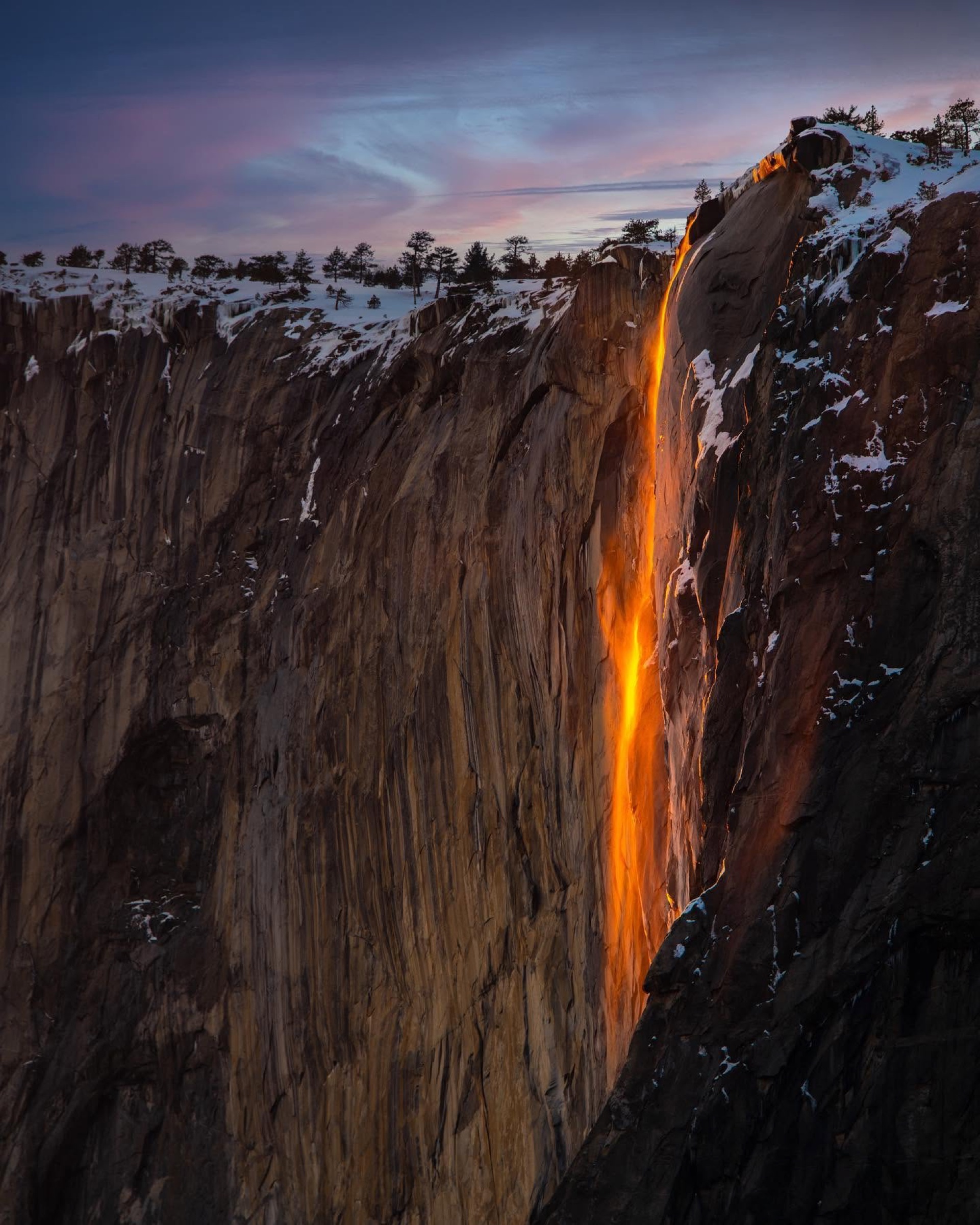 Orange light igniting a mountain ridge beneath storm clouds