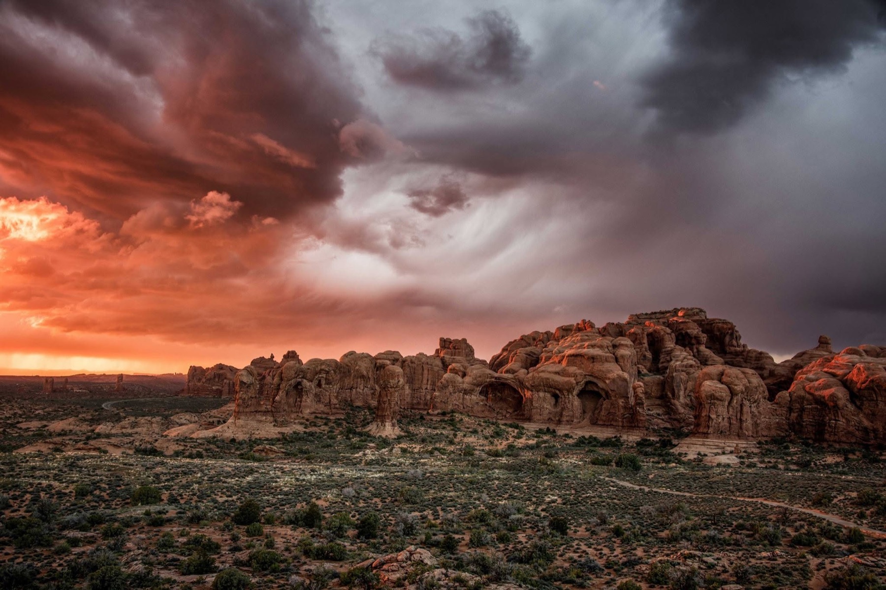 Red sandstone formations under a dramatic red and grey storm sky