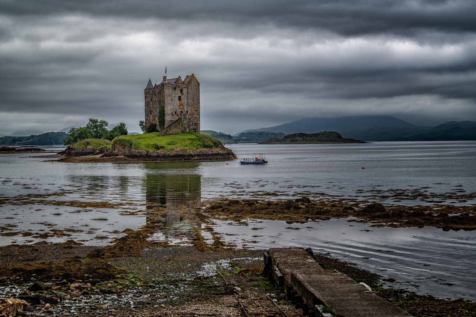 Castle Stalker standing on a tidal island beneath a heavy grey sky