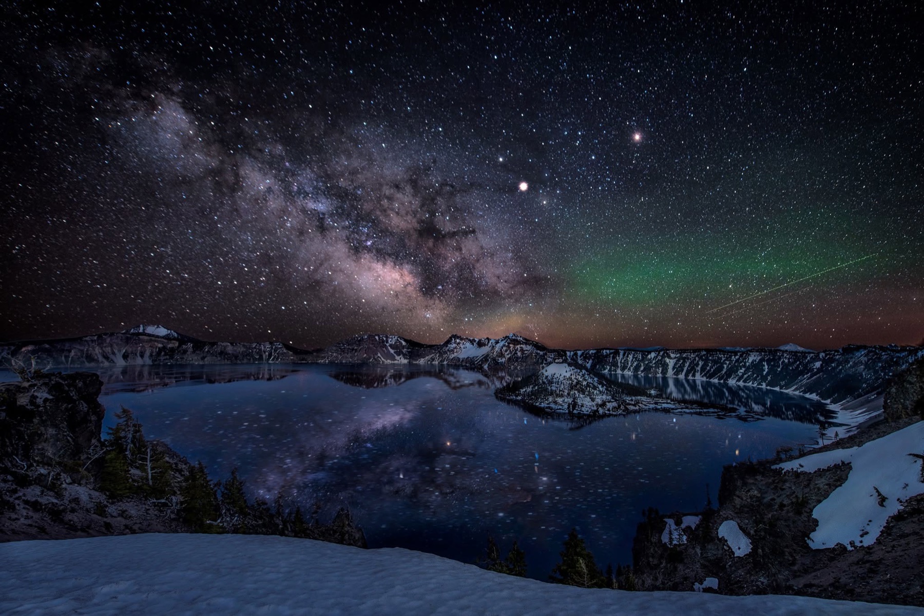 Milky Way and a faint green night glow reflected above snowy Crater Lake