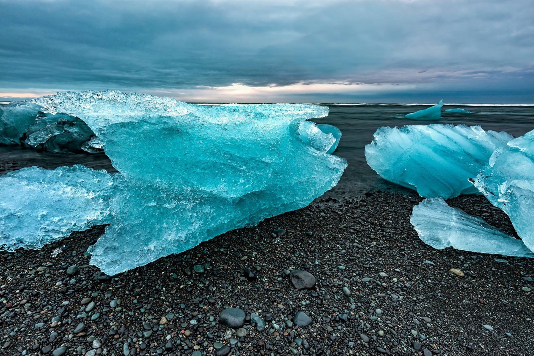 Blue glacier ice resting on a black volcanic beach