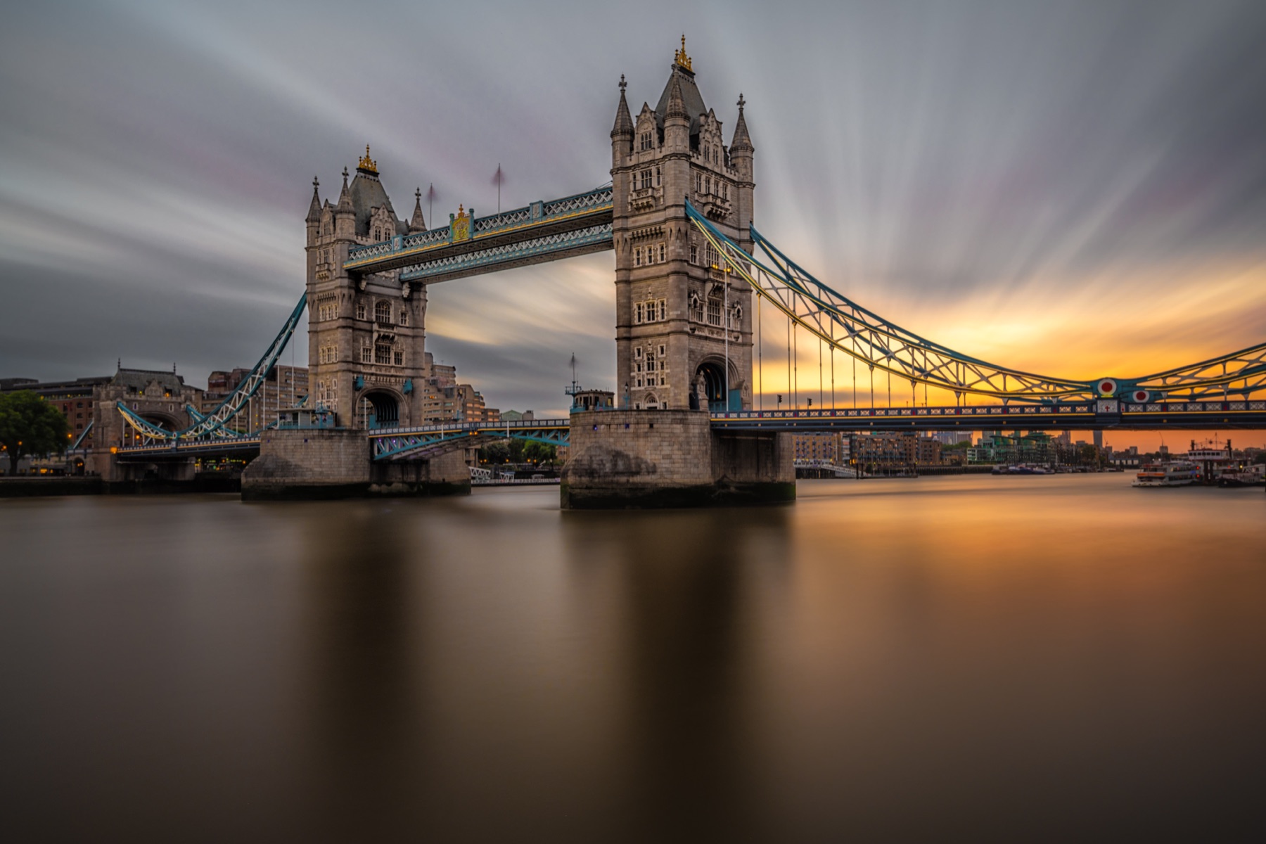 Tower Bridge reflected in smooth water beneath a soft evening sky
